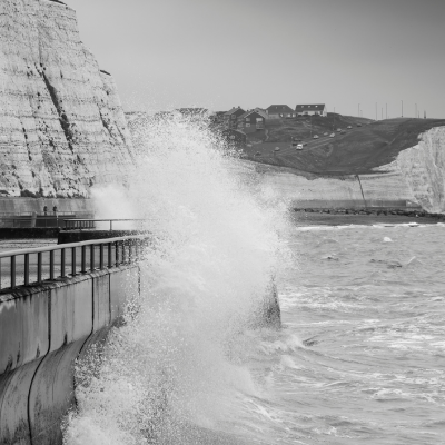 Waves crashing against a sea front with exposed steel structures, highlighting the need for corrosion-resistant coatings.