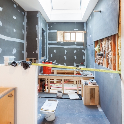 A partially constructed wet room with cement board walls, joint sealing, and a skylight above.