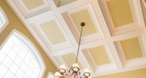 A traditional coffered ceiling with white beams and a large decorative chandelier.