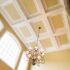 A traditional coffered ceiling with white beams and a large decorative chandelier.