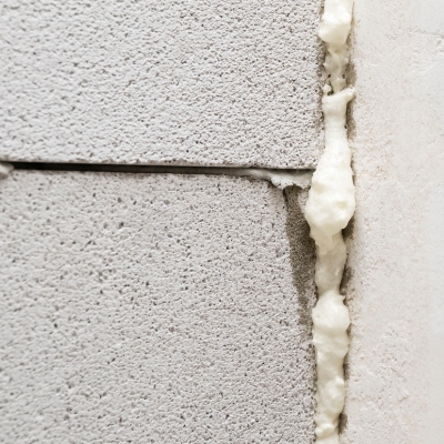 Expanding foam being applied between concrete blocks to seal gaps.