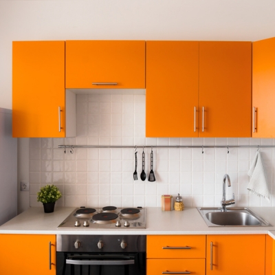 A contemporary kitchen with bright orange cabinets, a white tiled backsplash, and stainless steel appliances for a bold and energetic look.