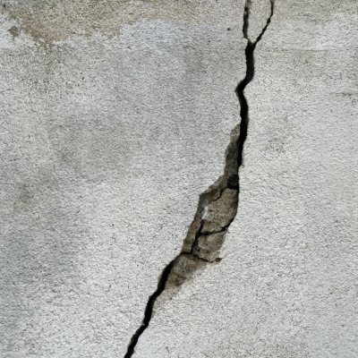 A deep crack in a concrete wall, requiring filler for repair.