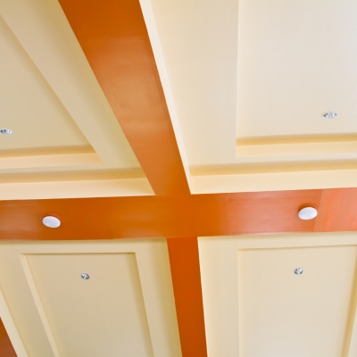 A coffered ceiling with beige panels and orange beams, featuring recessed lighting.