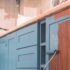 A modern kitchen with sage green cabinets, white worktops, and classic panelled doors, showing an updated look without full replacement.