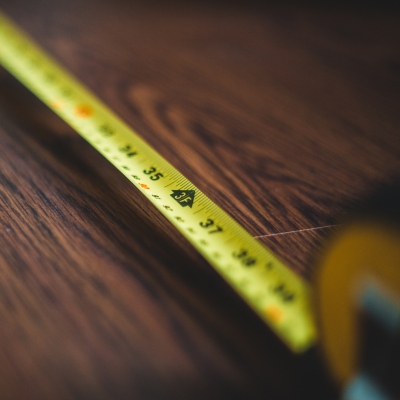 A yellow tape measure stretched out on a wooden floor, displaying measurement markings.